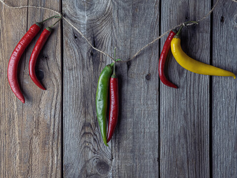 Vibrant chilies dangle against worn wooden planks