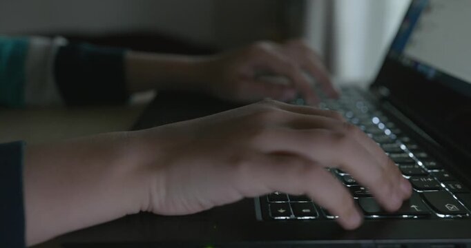 Close-up children's hands typing on laptop computer keyboard. 4K 10-bit