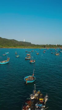 fishing boats and round coracle basket boats floating in sea bay near green mountain coastline in Danang Vietnam, aerial drone view, 4k vertical video