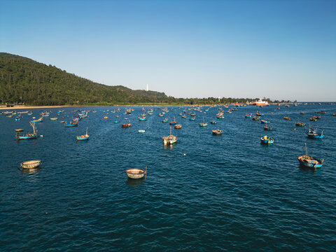 fishing boats and round coracle basket boats floating in sea bay near green mountain coastline in Danang Vietnam, aerial drone view