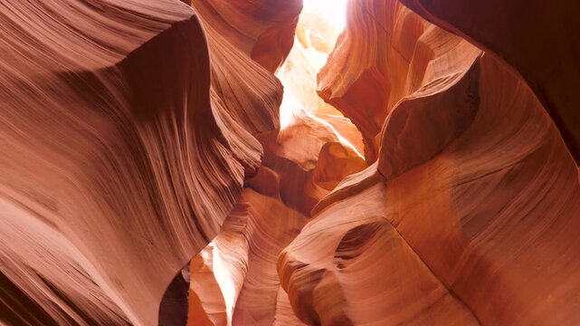 Sunlight illuminating smooth curving red rock walls inside antelope canyon, revealing natural sandstone erosion textures from low angle point of view. Fabulous sandstone textures created by nature.