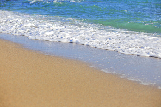 Close up of sea wave with white foam on a sandy beach