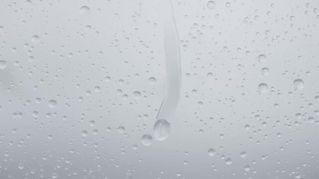 Forming smear, gravity-pulled droplets joining into vertical runoff bead on vertical pane