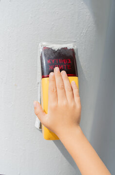 child's hand presses the button on a traffic light to cross an intersection