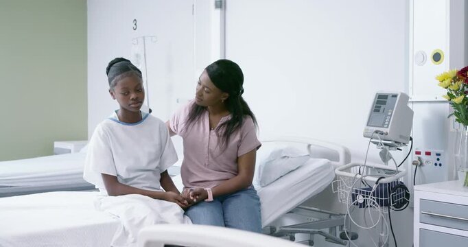 Female African American carer seeing withdrawn youth in gown on bed3 comforting