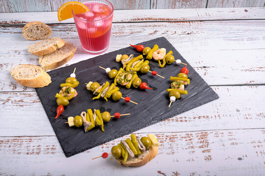 Homemade Spanish gilda pintxos with vermouth cocktail drink and bread on slate plate with copy space in Donosti, Basque Country