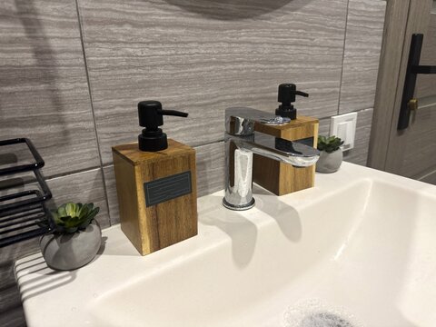 A clean, stylish washbasin with a faucet, liquid soap, and hand cream
