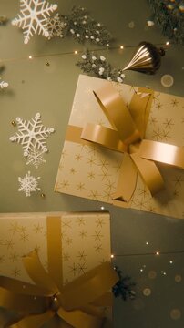 Vertical video: Twinkling LEDs causing two gifts catching warm glow on green table as festive decor