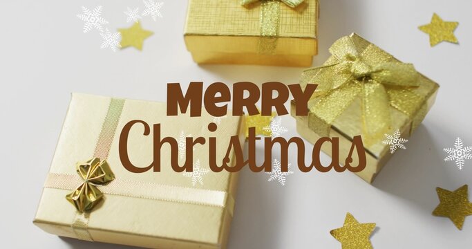 Showing three gold gifts with ribbons on white table, stars, snowflakes, brown MERRY Christmas