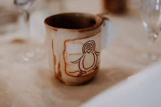 Handmade ceramic mug with penguin drawing on a table