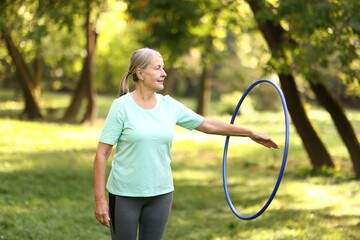 Senior woman exercising with hula hoop outdoors © New Africa
