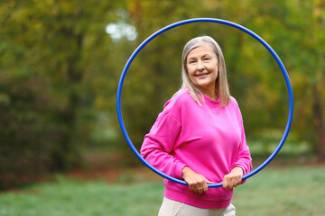 Senior woman with hula hoop in park, space for text © New Africa