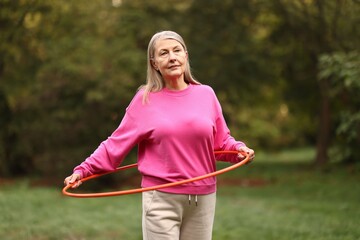 Senior woman exercising with hula hoop outdoors © New Africa