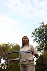 Senior woman exercising with hula hoop outdoors, low angle view © New Africa