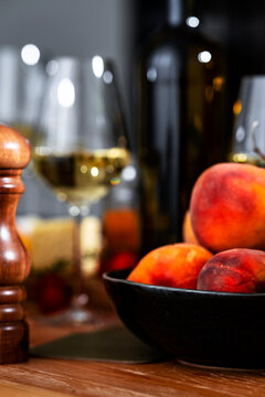 Fresh peaches in bowl with dry white wine glass and Sauvignon Blanc bottle - gourmet fruit food pairing concept for lunch. Elegant dinner table setup for luxury restaurant service.