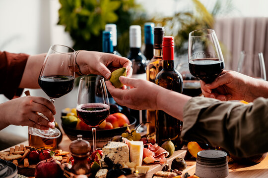 Red wine lunch table with family sharing fresh fig fruit - friends enjoying Merlot beverage tasting in autumn restaurant. Festive celebration and gourmet food pairing experience.