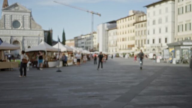 Florence city square blurred bokeh plaza with outdoor market tents and historic church facade in soft focus; background backplate copyspace calm.