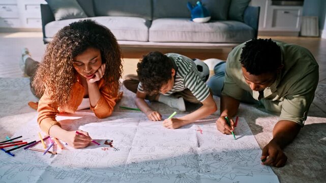 Parents son drawing markers lying living room floor. Family coloring together.