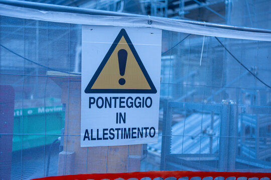 Italian construction warning sign Ponteggio in allestimento hanging on scaffolding netting in Rome, Italy