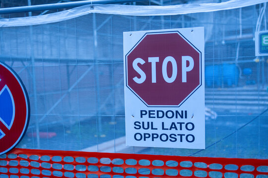 Italian stop sign reading pedestrians on the opposite side on a construction site fence in Rome, Italy