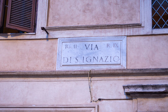 Marble street sign Via di S. Ignazio on a pink plastered building facade in Rome, Italy
