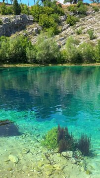 Clear turquoise water in a shallow lake with aquatic plants and rocky bottom