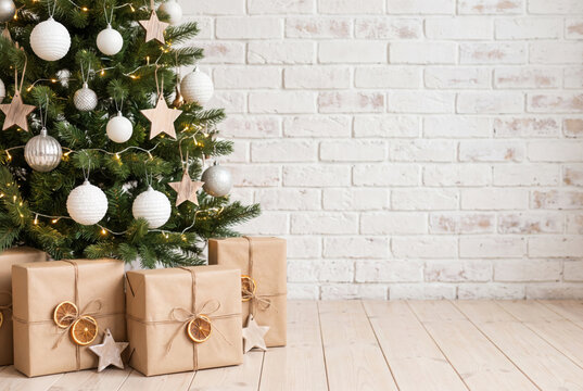 decorated christmas tree and gift boxes over white brick wall with copy space