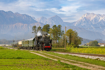 A nostalgic autumn moment as historic steam locomotive  pulls vintage passenger carriages along the quiet rural line from Kamnik to Ljubljana, framed by the majestic Kamnik-Savinja Alps and the  © erikzunec
