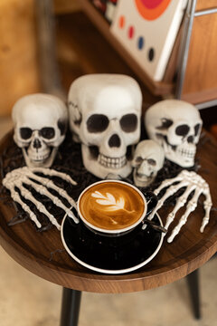 Halloween celebrated coffee,Close up of Hot coffee latte with latte art milk foam in cup mug with decor in a coffee a theme of halloween on wood desk Halloween holiday background.
