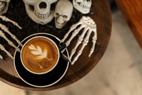 Halloween celebrated coffee,Close up of Hot coffee latte with latte art milk foam in cup mug with decor in a coffee a theme of halloween on wood desk Halloween holiday background.