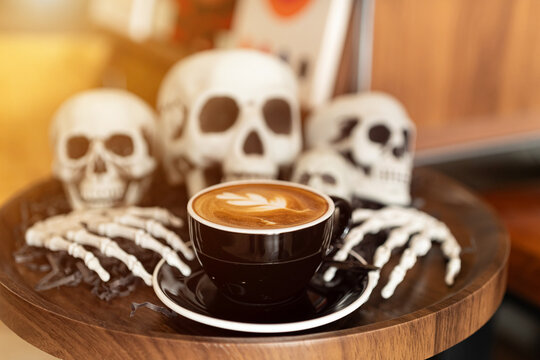 Halloween celebrated coffee,Close up of Hot coffee latte with latte art milk foam in cup mug with decor in a coffee a theme of halloween on wood desk Halloween holiday background.