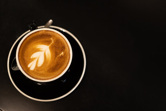 Hot coffee latte with latte art milk foam in cup mug on wood desk on top view. As breakfast In a coffee shop at the cafe,during business work concept,vintage style