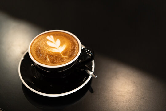 Hot coffee latte with latte art milk foam in cup mug on wood desk on top view. As breakfast In a coffee shop at the cafe,during business work concept,vintage style