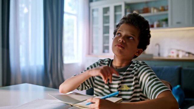 Pupil solving homework kitchen table. Thoughtful kid thinking writing notebook.