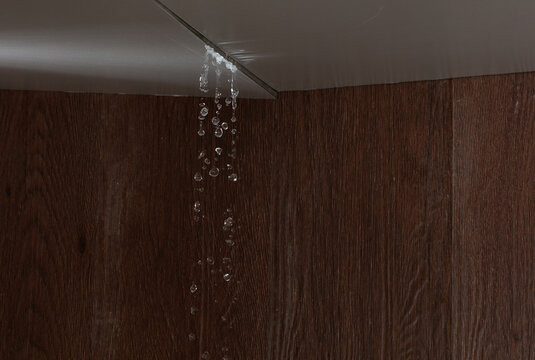 Heavy storm rain create water flow from edge of ceiling and dirty stain on wall. Water leaking from top ceiling as droplets and flow in old house