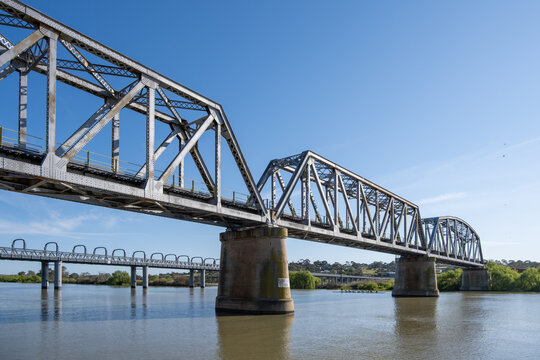 A historic steel truss railway bridge spans the Murray River at Murray Bridge, South Australia. Concepts of heritage engineering, transport infrastructure, and regional inland waterway.