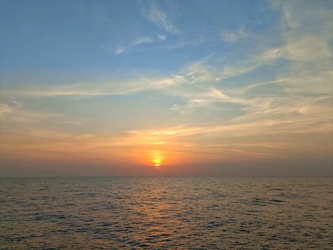 Golden sunset over ocean horizon with sun light reflecting on sea water surface
