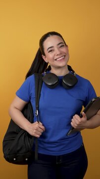 Cheerful latina college student holding tablet and backpack