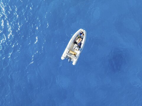 Young woman and young man lying in a motor boat on a blue sea, top-down, aerial view, Golfo di Orosei, Baunei, Sardinia, Italy