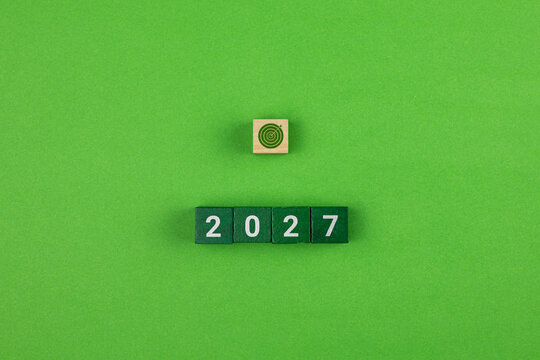 A concept featuring stacked wooden cubes with icons and an arrow, where 2027 represents the year for achieving goals and aspirations. Green color palette.