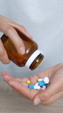 close up woman hand holding a medicine, with pours the pills out of medicine bottle. Stop drug use Taking Medication Caring for the health care medical concept.