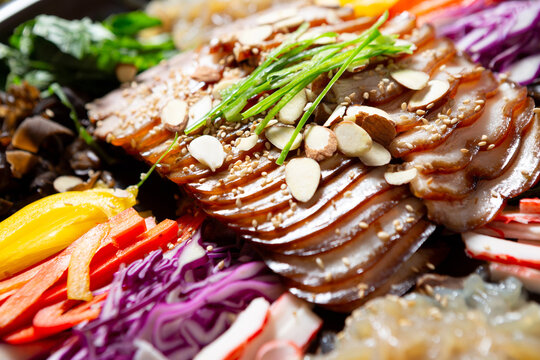 Gourmet Korean chilled trotter salad known as Naengchae-jokbal topped with almond flakes, chives, and assorted colorful vegetables