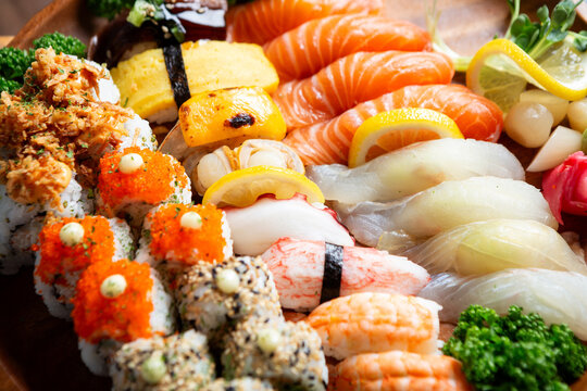 Gourmet Japanese assorted sushi platter with salmon, white fish, shrimp, tamago nigiri, and sushi rolls on a wooden tray