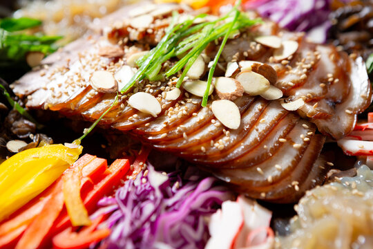 Gourmet Korean chilled trotter salad known as Naengchae-jokbal topped with almond flakes, chives, and assorted colorful vegetables