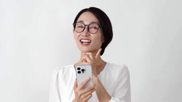 スマホを持って想像するミドル女性　白背景　スローモーション
