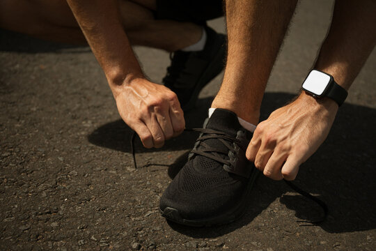 Runner prepares for exercise by tying shoelaces on a sunny day