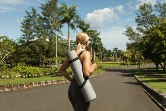 Jogger with yoga mat enjoying a sunny day in a peaceful park