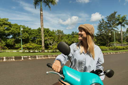 Woman enjoys a ride on her scooter surrounded by greenery