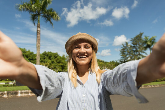 Woman happily greets camera with sunny skies above