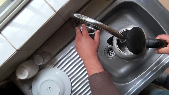 Top-down stock video of a person filling an electric kettle with tap water in the kitchen
